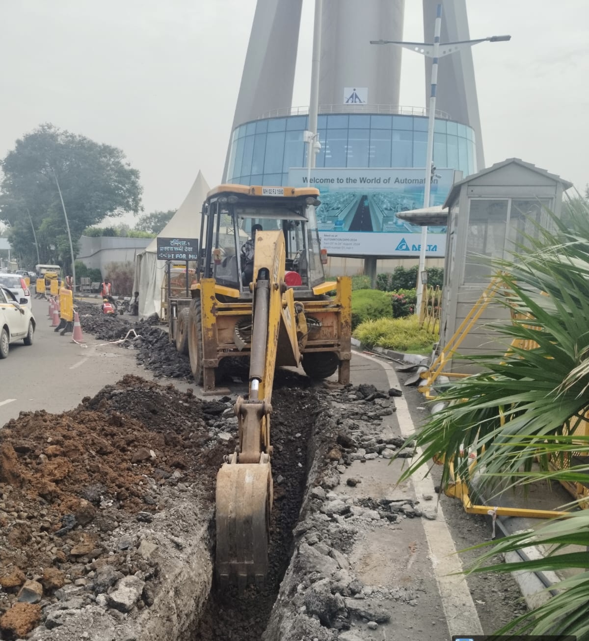 Backhoe excavating a cable trench near a landmark building