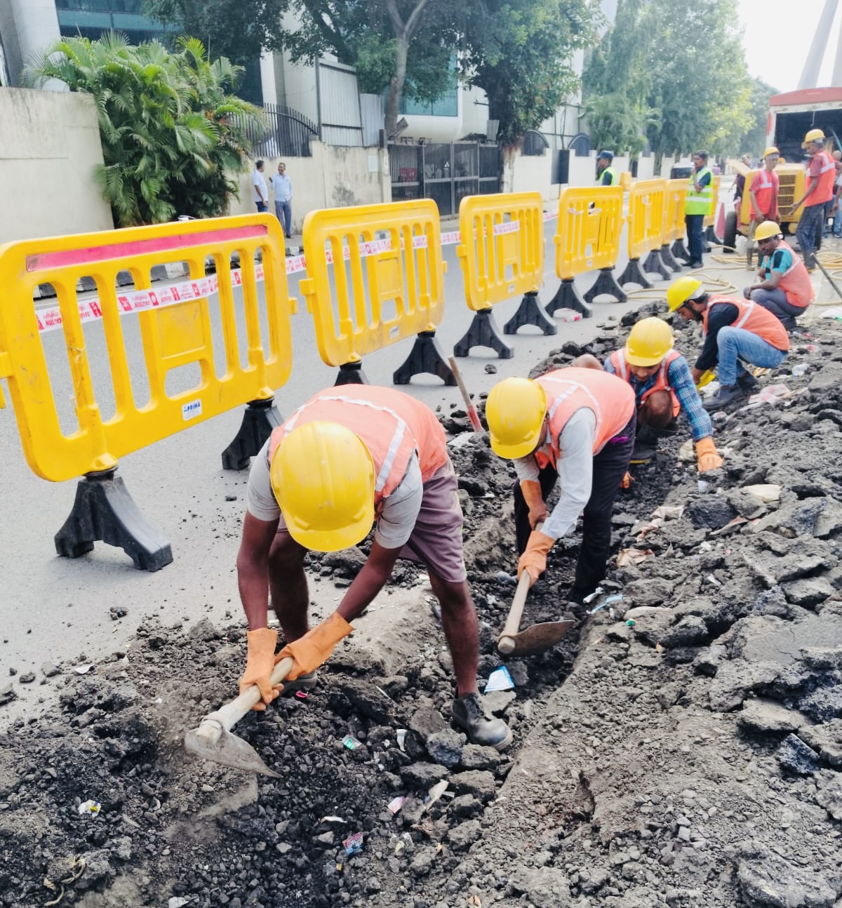 Team clearing a roadside trench with safety barricades in place