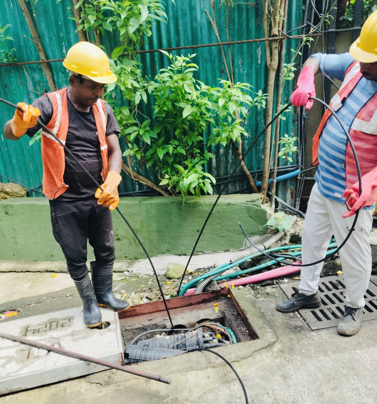 Technicians pulling fiber cable from an underground access chamber
