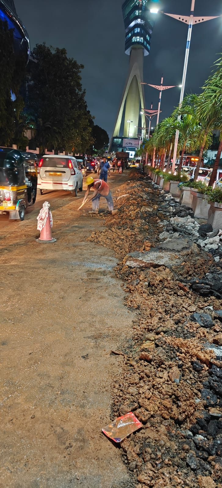 Night-time reinstatement work along a city road near a landmark tower